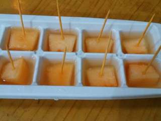 6、蜜瓜遇上冰,这是另一种做法，哈蜜瓜切大丁，放入冰格，在哈蜜瓜中间插上牙签，每格都倒入蜂蜜水，同样放进冰箱冷冻一夜