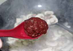 5、韩式辣酱蘑菇烧豆腐,然后加入一勺辣椒酱，翻炒下立马下入小半碗水搅拌均匀，倒入豆腐