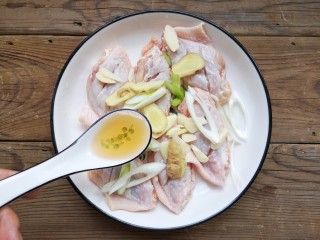 4、咸蛋黄鸡翅,将打好花刀的鸡翅放入容器中，加入葱姜蒜片，加适量的料酒。