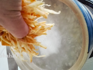 6、红薯丝粥,煮五分钟后放入地瓜丝，用饭勺搅拌几下，避免沾锅底。