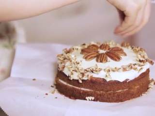 13、胡萝卜蛋糕,然后再抹一些糖霜上去,抹平整,把完整的核桃放中间,把碎的撒在四周即可