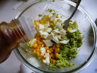 4、牛油果色拉盅,把牛油果果泥、水煮鸡蛋碎和玉米混合并加入撕碎的芝士片拌匀后，把混合物装入牛油果果壳中。