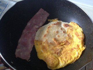 6、鸡蛋灌饼卷苹果培根 ,将加了少许盐的鸡蛋液灌入饼中，继续双面烙。旁边顺便煎条培根。