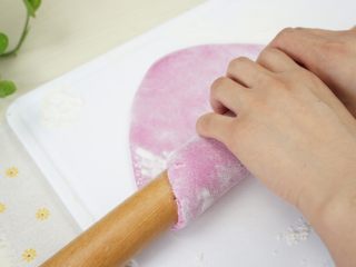 7、手工面,稍微大一点后，在面皮上面撒一层干面粉，用擀面杖卷起面饼的一端。