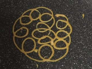 9、宝宝辅食之网格蛋卷,把裱花袋剪开一个细细的小口。热锅开小火,不加油,一圈一圈,从里向外挤成蛋饼即可。