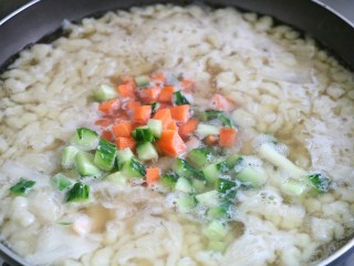 12、虾仁疙瘩汤,面全部压好后，将虾仁和胡萝卜、黄瓜丁放入改中火煮熟