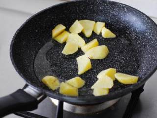 3、黑椒煎牛排,准备配菜，土豆去皮切成块，平底锅加油烧热，放入土豆小火煎至两面金黄色。