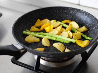 4、黑椒煎牛排,土豆块煎至差不多的时候，放入洗净的芦笋和黄甜椒块翻炒至断生，撒少许盐和黑胡椒翻炒均匀即可出锅。
