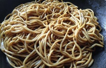 4、黯然销魂炒面,淋1小勺芝麻油在面条上,并拌匀;加入半勺生抽和1/3勺老抽拌匀,使面条上色;