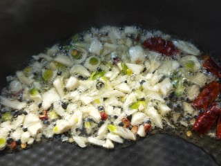 16、美味酸萝卜炒腊鸭心,起油锅，放干辣椒、花椒粒、蒜末小火煸出香味。