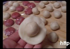 4、荷花酥,拿一个水油皮剂子按扁，放一个油酥剂子，捏紧封口，收口朝下放案板上；