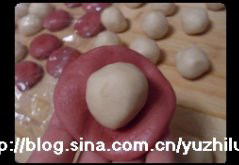 7、荷花酥,从上至下卷起来，盖保鲜膜备用，拿一个红色水油皮面团，包裹油酥面团，捏紧封口，收口朝下放案板上；