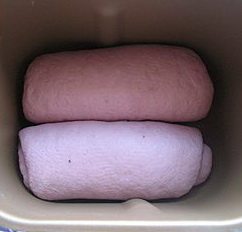 14、紫薯红豆沙吐司,把卷好红豆沙的面团放入面包桶内。