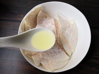 5、烤芋头片,把切好的芋头片装入碗中，加一勺油。