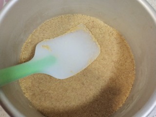 5、镜面芒果慕斯蛋糕,准备一个6寸的活底蛋糕模具，底部铺上油纸，把和无盐黄油拌好的饼干碎倒入模具，用刮刀压实，一定要压实，不压实脱膜的时候会散掉哦，然后放入冰箱冷藏一会