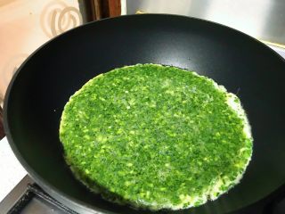 9、春游食谱~韭菜煎蛋,晃动锅子,让蛋液均匀铺在锅底。