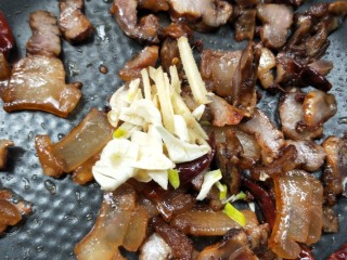 11、鲜香辣杏鲍菇炒腊肉,接着放蒜，姜一起小火煸炒。