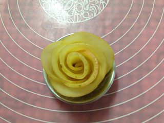 11、苹果玫瑰花,将面团 从一头向另一头卷起来，卷成玫瑰花，放入模具里