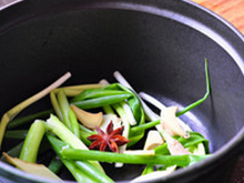 2、把子肉,砂锅（我用铸铁锅）底部铺上大段香葱和大块儿生姜，并加入一粒八角