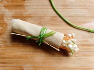 7、豆皮金针菇卷,卷好的豆皮卷用焯过水的香菜扎起来。
