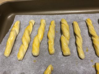 11、宝宝橙汁磨牙棒,面条首位旋转,扭起来,另一个剩的鸡蛋黄打散,刷在扭扭条上,放入铺了油纸的烤盘上