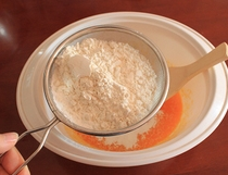 4、电饭煲版戚风蛋糕,筛入富强粉和玉米淀粉的混合物，拌匀。