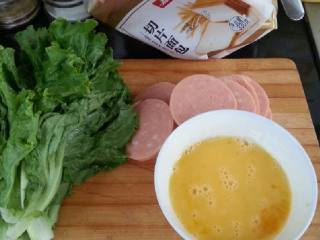 1、三明治-越简单越美味~,两个鸡蛋晃一晃打到碗里(这样可以避免蛋液浪费哦)火腿选自己喜欢的口味就好,我这个4.5元一大块,切片备用,生菜叶洗净备用