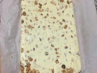 6、牛轧糖,倒入提前铺好油纸的烤盘里，使劲压平，大概2厘米厚