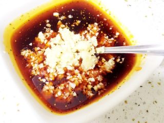 4、地方菜-蒜泥白肉,把蒜末倒入拌好的红油里。