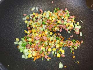 6、百变鸡蛋+福袋饭,接着把火腿碎和玉米粒放入锅中翻炒。