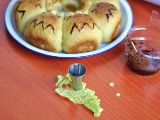 12、龙猫挤挤面包,出炉后冷却，用融化的巧克力画上龙猫的嘴巴、胡子，用圆形裱花嘴在白菜叶刻出小圆点做眼睛，中间点上巧克力做眼球