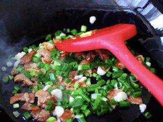 6、培根鸭蛋杂蔬炒饭,看见培根炒出香味后,放入切末的葱花末继续翻炒出香味;