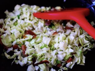 7、培根鸭蛋杂蔬炒饭,待小香葱爆香后,再加入切碎的包菜继续翻炒片刻后;