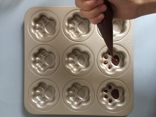 10、猫爪蛋糕,可可粉面糊装入裱花袋中挤上猫爪的肉垫。
