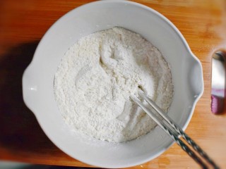 2、紫薯烧饼,将糯米粉与面粉混合倒入大的容器中，用筷子轻轻的拌匀。