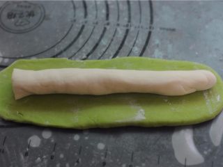 7、让人不忍心下口的——翡翠饺子,将菠菜面团擀成长方形，白面团搓成长柱形，放在菠菜面团上面