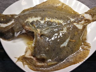 17、清蒸多宝鱼,八分钟到后，端出多宝鱼，去除鱼身和腹部的葱姜，倒掉蒸出来的水。