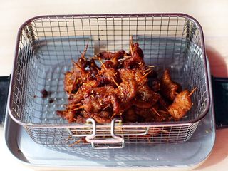 9、秘制牙签肉,锅内放油，烧至七成热，下入穿好的牙签肉炸至表面微微泛黄，然后捞起放沥水篮沥干油份。