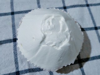 12、可爱的圣诞杯子蛋糕,把纸杯放入烤箱里170度烤20分钟。烤好后放凉。把淡奶油加入10克糖打发，然后用抹刀在纸杯蛋糕上做出圣诞老人的头。草莓没有买到，圣诞老人的帽子用小番茄代替了。