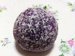 5、草莓椰蓉紫薯球,取一份紫薯包着一个草莓捏成一个圆球后把它放到椰蓉上滚动粘上。