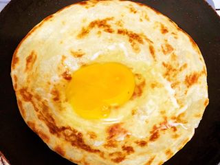 7、香酥黑椒手抓饼,小火煎至两面金黄,将鸡蛋????打到饼皮上煎制,待蛋白发白凝固后,将饼皮翻一个面继续煎制30秒,轻轻晃动锅,避免粘锅变糊,影响口感。