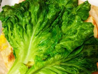 9、香酥黑椒手抓饼,将煸炒的生菜叶放置到有鸡蛋的饼皮面,尽量全覆盖(在制作完成食用时,每一口都能面面俱到)