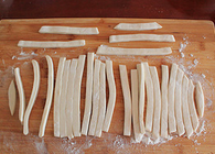 6、炒猫耳朵,放一些面粉防粘,然后将面饼切成约0.5cm宽的条。