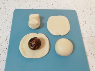 12、枣泥核桃卷,让两头翘起，压扁擀成圆形，放入枣泥核桃馅，用虎口慢慢向上推挤捏紧收口。