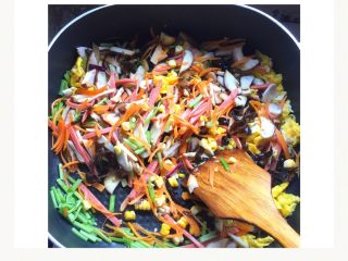 4、五颜六色炒米线#面条变身计划#,倒入配菜：蘑菇片、胡萝卜丝、芹菜杆、黑木耳、玉米粒、火腿肠丝翻炒至有香味。