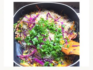 6、五颜六色炒米线#面条变身计划#,加入适量的食用盐和蔬菜精，加入紫甘蓝丝和香菜碎翻炒，加入少许的清水焖一会儿。