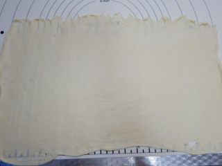 10、椰蓉蔓越莓花环面包,用擀面杖把面团擀成50×35cm的长方形，上边缘压薄，，可以借助刮刀均匀摊平， 注意尺寸，不要差太多，不然做出的花环可能会小。