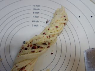 14、椰蓉蔓越莓花环面包,像拧麻花一样，把两条边交叉拧在一起，切口尽量朝上。