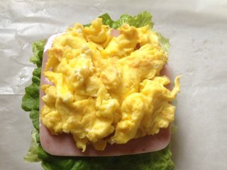 5、纸袋三明治,铺上2片火腿片,再放上炒鸡蛋;