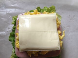 6、纸袋三明治,再铺上2片芝士片,再铺上2片火腿片;